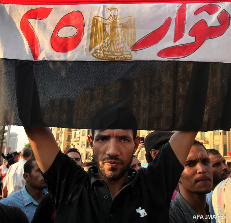 An Egyptian protester holds his national flag bearing the slogan "Revolutionaries of the 25th", refering to the revolution of January 25 that toppled president Hosni Mubarak, during a protest against the expansion of the...