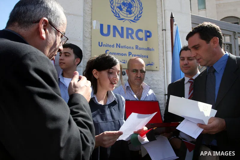 Palestinian school girl, left, hands a letter, addressed to the United Nations Secretary-General Ban Ki-moon, to UN officer Pascale Soto, right, during a rally to support the Palestinian statehood bid in the United Natio...