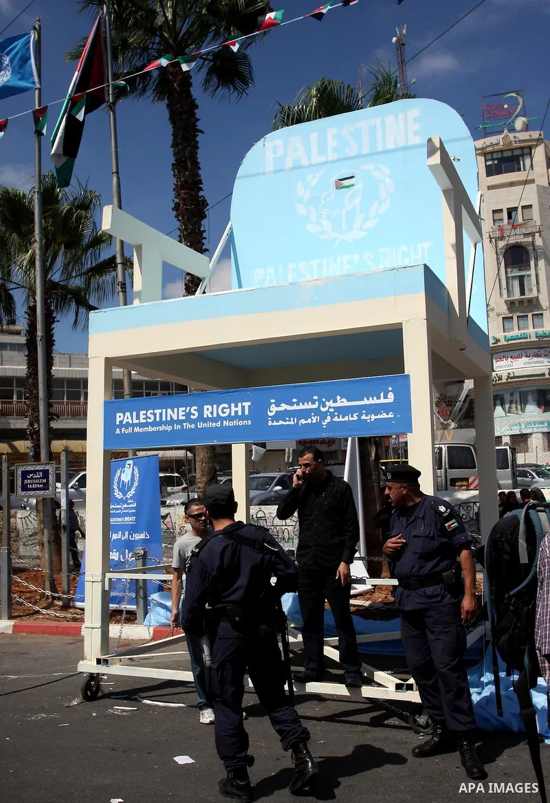 Palestinian police stand while the palestinians applaud in front of a symbolic chair supporting the Palestinian statehood bid in the West Bank city of Ramallah, unveiled on Sept. 20, 2011. Palestinian President Mahmoud A...