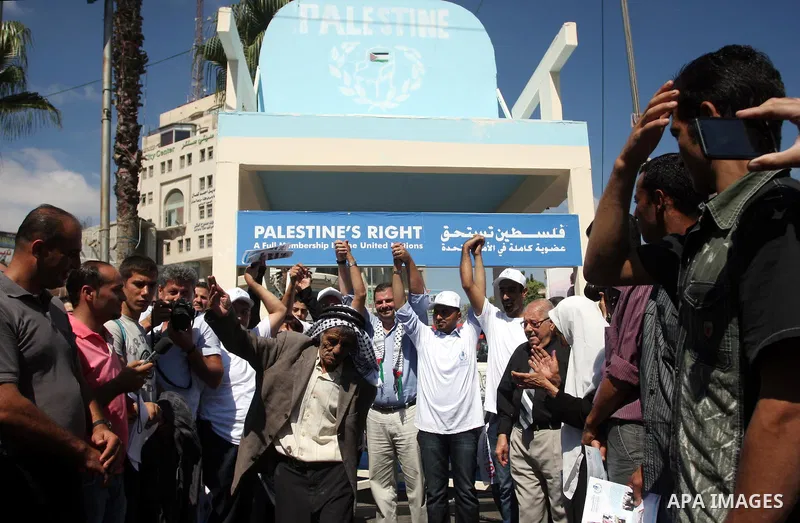 Palestinians celebrate while carrying a symbolic seat for Palestine in the UN in support for Palestinian statehood, at Manara square in the West Bank town of Ramallah, on 20 September 2011, few days before the vote in th...