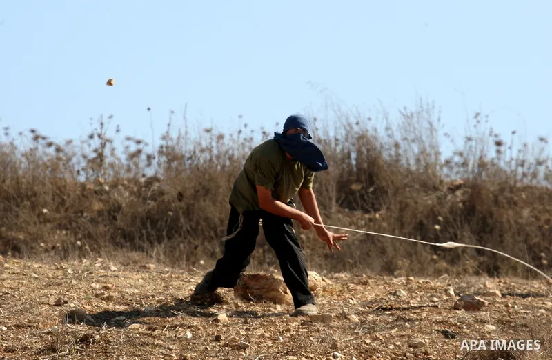 Masked Jewish settlers throw stones toward Palestinians in the West Bank village of Assira al-Kibliya, near Nablus Tuesday, Sept. 20, 2011. Israeli settlers and Palestinian villagers threw stones at each other Tuesday, a...