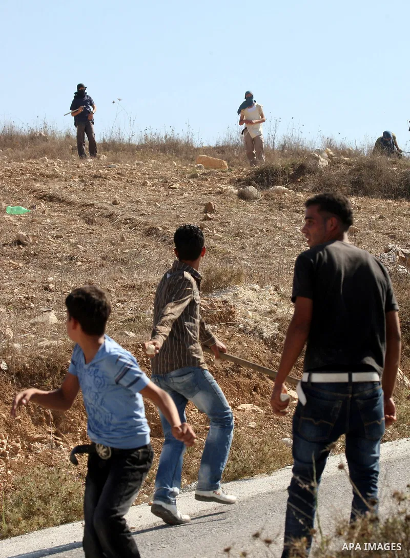 Palestinian youths throw stones toward Jewish settlers in the West Bank village of Assira al-Kibliya, near Nablus Tuesday, Sept. 20, 2011. Israeli settlers and Palestinian villagers threw stones at each other Tuesday, a...