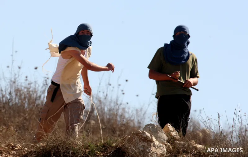 Masked Jewish settlers throw stones toward Palestinians in the West Bank village of Assira al-Kibliya, near Nablus Tuesday, Sept. 20, 2011. Israeli settlers and Palestinian villagers threw stones at each other Tuesday, a...