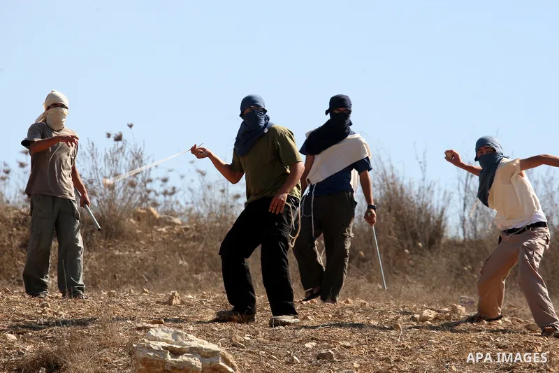 Masked Jewish settlers throw stones toward Palestinians in the West Bank village of Assira al-Kibliya, near Nablus Tuesday, Sept. 20, 2011. Israeli settlers and Palestinian villagers threw stones at each other Tuesday, a...