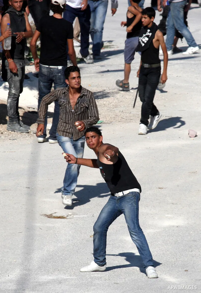Palestinian youths throw stones toward Jewish settlers in the West Bank village of Assira al-Kibliya, near Nablus Tuesday, Sept. 20, 2011. Israeli settlers and Palestinian villagers threw stones at each other Tuesday, a...
