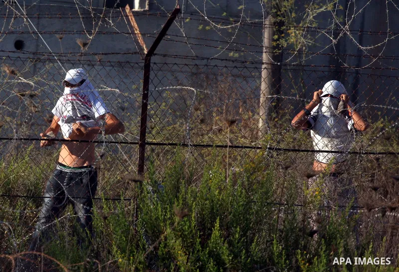 Masked Jewish settler boys from the Israeli West bank settlement of Bet El, throw stones at Palestinians Near the refugee camp of Jalazoun in the West Bank city of Ramallah on September 20, 2011. Reports state that Pales...
