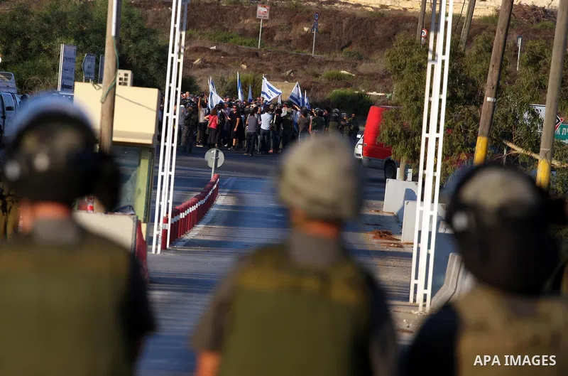 Israeli soldiers keep watch as Jewish settlers hold Israeli flags during a protest against the Palestinian bid for statehood at the United Nations on September 20 , 2011, close at the Jewish settlement of Beit El, in the...