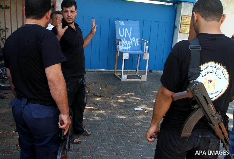 Palestinian Hamas police stand near the Palestinian carpenter Mustafa Masoud, 24, takes a chair symbolizing the Palestinian statehood bid from his house to be placed in front of the UN offices in Gaza city, Wednesday, Se...