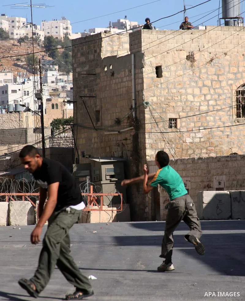 Palestinian youths throw stones towards Israeli soldiers during a protest in the West Bank city of Hebron 21 September 2011, as Palestinian president Mahmud Abbas prepares to submit a formal request for Palestine to beco...