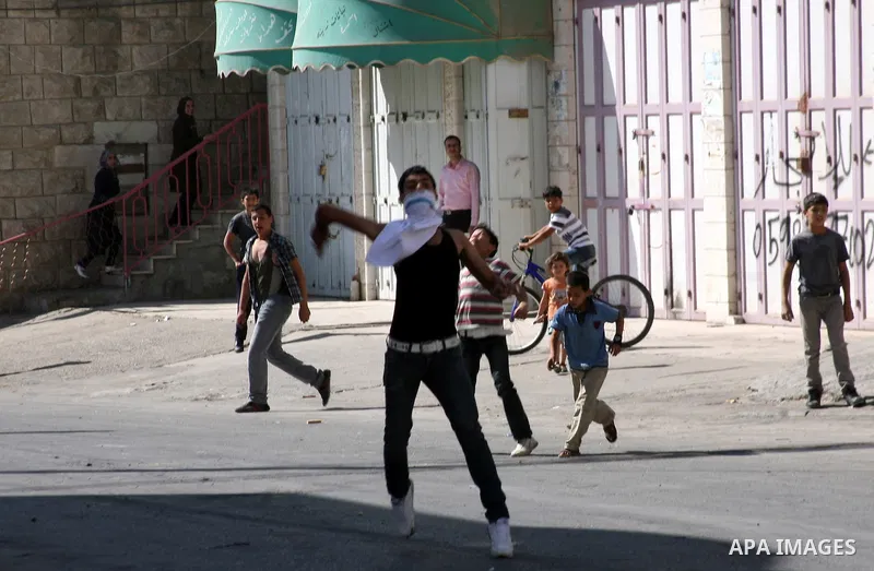 Palestinian youths throw stones towards Israeli soldiers during a protest in the West Bank city of Hebron 21 September 2011, as Palestinian president Mahmud Abbas prepares to submit a formal request for Palestine to beco...