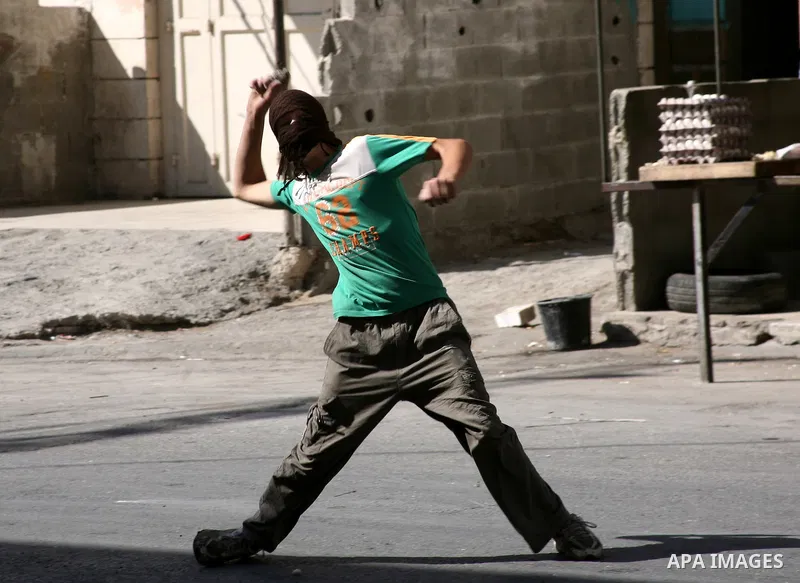Palestinian youths throw stones towards Israeli soldiers during a protest in the West Bank city of Hebron 21 September 2011, as Palestinian president Mahmud Abbas prepares to submit a formal request for Palestine to beco...