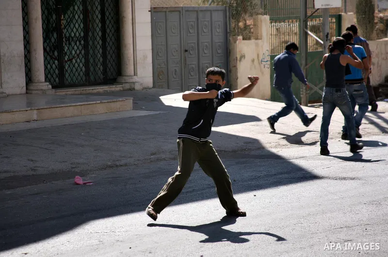 Palestinian youths throw stones towards Israeli soldiers during a protest in the West Bank city of Hebron 21 September 2011, as Palestinian president Mahmud Abbas prepares to submit a formal request for Palestine to beco...