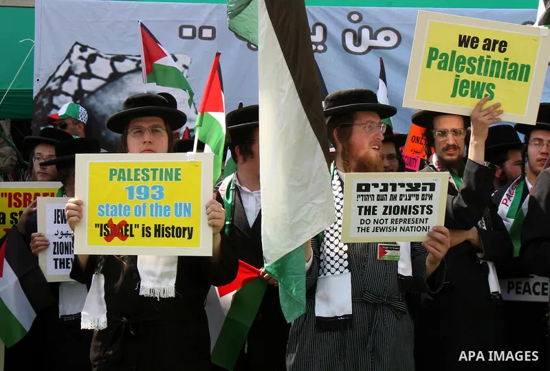 Members of Neturei Karta, a small faction of ultra-Orthodox Jews who oppose Israel's existence, hold placards to express support for the Palestinian bid for statehood recognition at the United Nations as thousands of Pal...