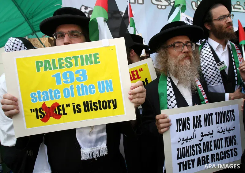 Members of Neturei Karta, a small faction of ultra-Orthodox Jews who oppose Israel's existence, hold placards to express support for the Palestinian bid for statehood recognition at the United Nations as thousands of Pal...