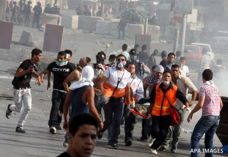 Paramedics help a Palestinian protester, injured in his eye by a tear gas canister fired by Israeli soldiers during clashes at the Qalandia checkpoint between the West Bank city of Ramallah and Jerusalem, Wednesday, Sept...