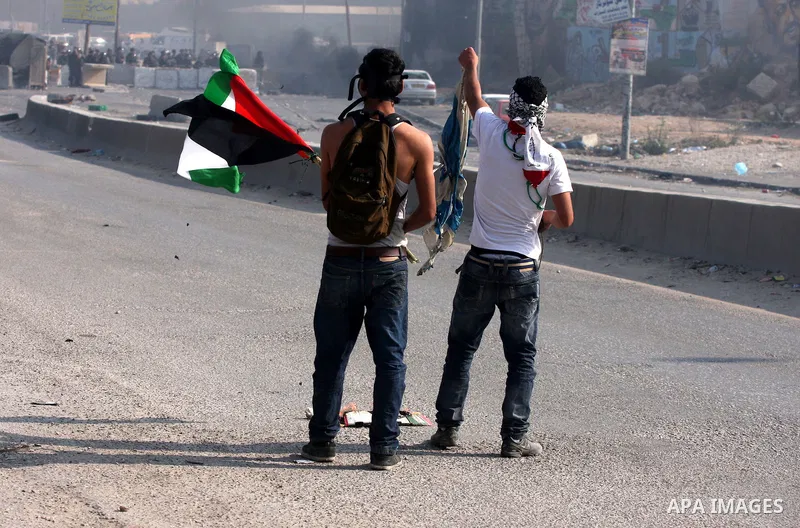 A Palestinian protester waves his national flag in front of Israeli soldiers during clashes at the Qalandia checkpoint between the West Bank city of Ramallah and Jerusalem, Wednesday, Sept. 21, 2011. Palestinians clashed...