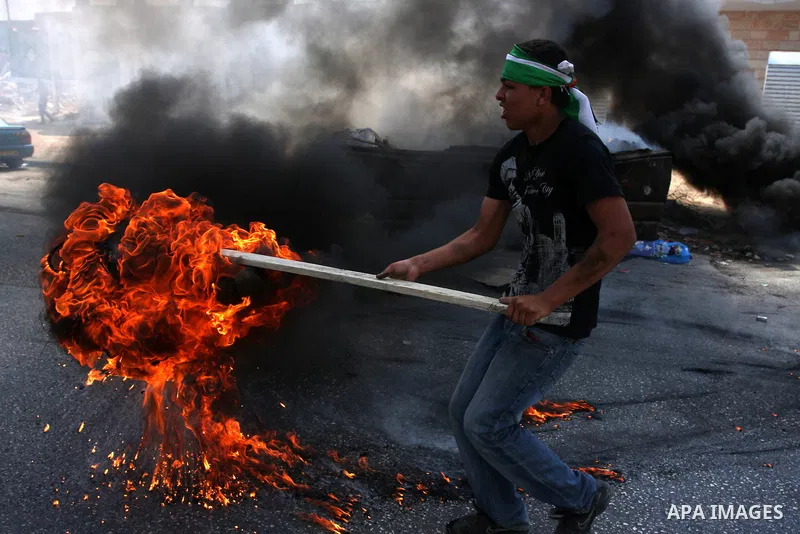 A Palestinian protester burns tyres during clashes with Israeli soldiers at the Qalandia checkpoint between the West Bank city of Ramallah and Jerusalem, Wednesday, Sept. 21, 2011. Palestinians clashed with Israeli secur...