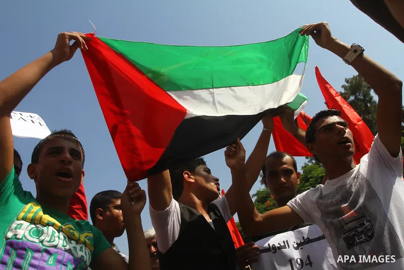 Palestinian men chant slogans and wave their national flag during a demonstration in support of Palestinian leader Mahmud Abbas' bid for statehood recognition at the United Nations on September 22, 2011 in Gaza City. Pho...