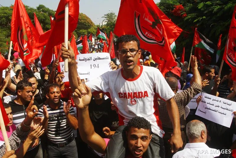 Palestinian men chant slogans and wave their national flag during a demonstration in support of Palestinian leader Mahmud Abbas' bid for statehood recognition at the United Nations on September 22, 2011 in Gaza City. Pho...