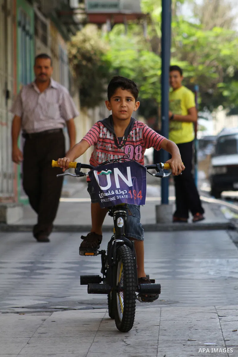 A Palestinian boy rides a bicycle decorated with a sign supporting the Palestinians' bid in the United Nations for statehood recognition, on September 23, 2011 in Gaza City. Palestinian president Mahmud Abbas will presen...