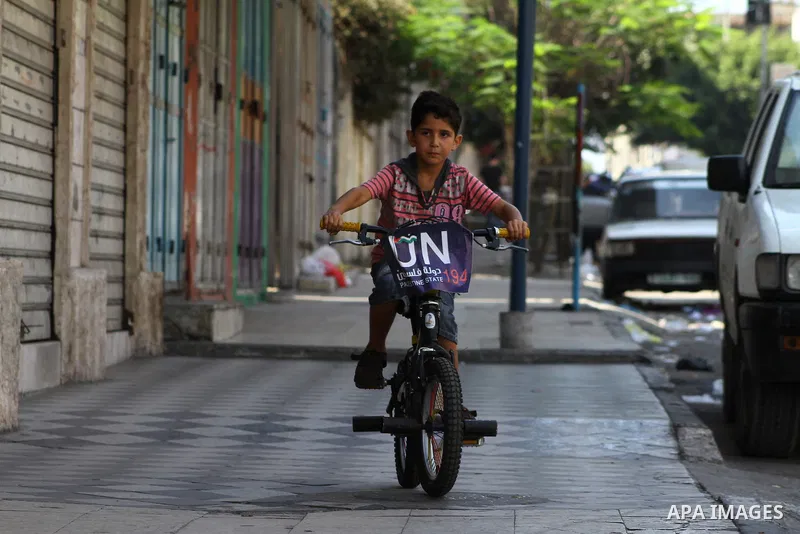 A Palestinian boy rides a bicycle decorated with a sign supporting the Palestinians' bid in the United Nations for statehood recognition, on September 23, 2011 in Gaza City. Palestinian president Mahmud Abbas will presen...