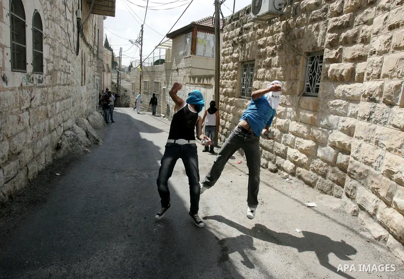 Palestinian youths throw stones toward Israeli border police during clashes in the east Jerusalem neighborhood of Ras al-Amud on September 23, 2011, just hours before their president, Mahmoud Abbas, was to deliver his wi...