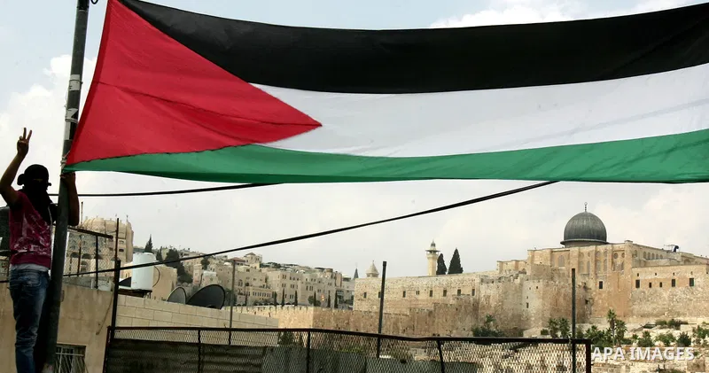 A masked Palestinian holds a Palestinian flag in the East Jerusalem neighbourhood of Ras al-Amud September 23, 2011. Palestinian President Mahmoud Abbas asks the United Nations on Friday to recognize a state for his peop...