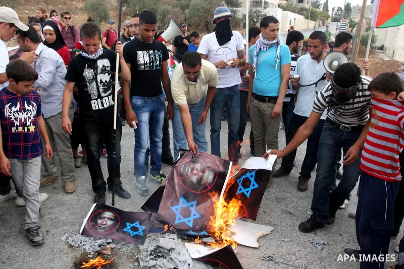 Palestinian protesters burn an Israeli flag and a poster depicting U.S. President Barack Obama at a weekly protest in the West Bank village of Nabi Saleh, near Ramallah September 23, 2011. Israeli security forces were on...