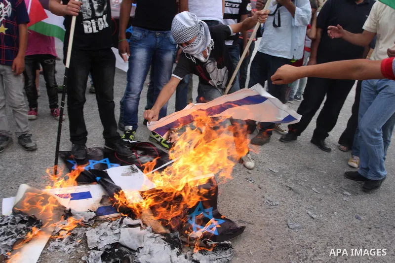 Palestinian protesters burn an Israeli flag and a poster depicting U.S. President Barack Obama at a weekly protest in the West Bank village of Nabi Saleh, near Ramallah September 23, 2011. Israeli security forces were on...