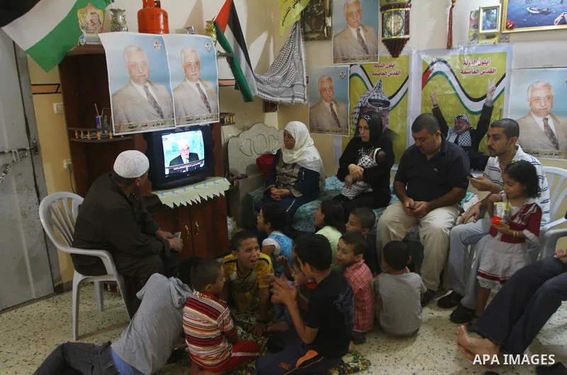 A Palestinian family watches as their president Mahmud Abbas addresses the General Assembly of the United Nations, in Gaza City on September 23, 2011 where he called on the UN to admit a state of Palestine as a full memb...
