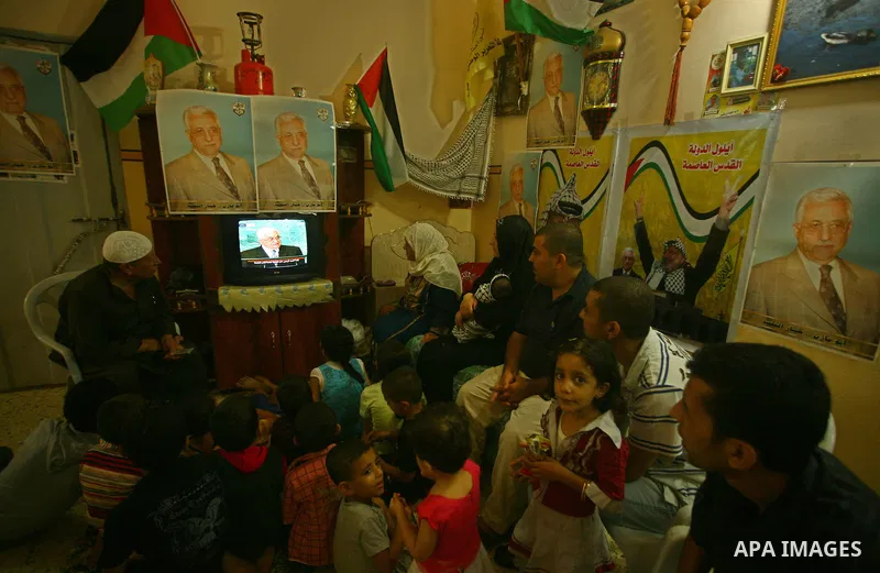 A Palestinian family watches as their president Mahmud Abbas addresses the General Assembly of the United Nations, in Gaza City on September 23, 2011 where he called on the UN to admit a state of Palestine as a full memb...