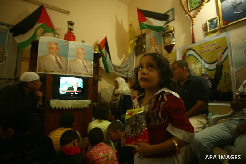 A Palestinian family watches as their president Mahmud Abbas addresses the General Assembly of the United Nations, in Gaza City on September 23, 2011 where he called on the UN to admit a state of Palestine as a full memb...