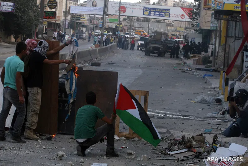 Palestinian men throw stones at Israeli soldiers during riots at the Qalandia checkpoint near Ramallah, on 23 September 2011. Reports state that Israeli security services were on high alert across the country, poised to...