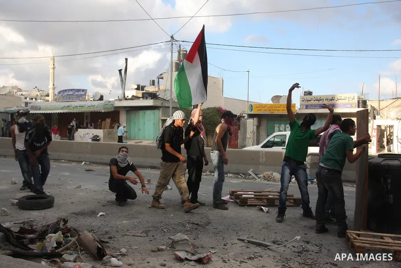 Palestinian men throw stones at Israeli soldiers during riots at the Qalandia checkpoint near Ramallah, on 23 September 2011. Reports state that Israeli security services were on high alert across the country, poised to...