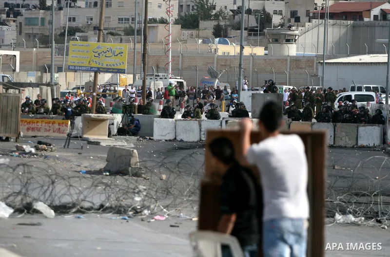 Palestinian men throw stones at Israeli soldiers during riots at the Qalandia checkpoint near Ramallah, on 23 September 2011. Reports state that Israeli security services were on high alert across the country, poised to...