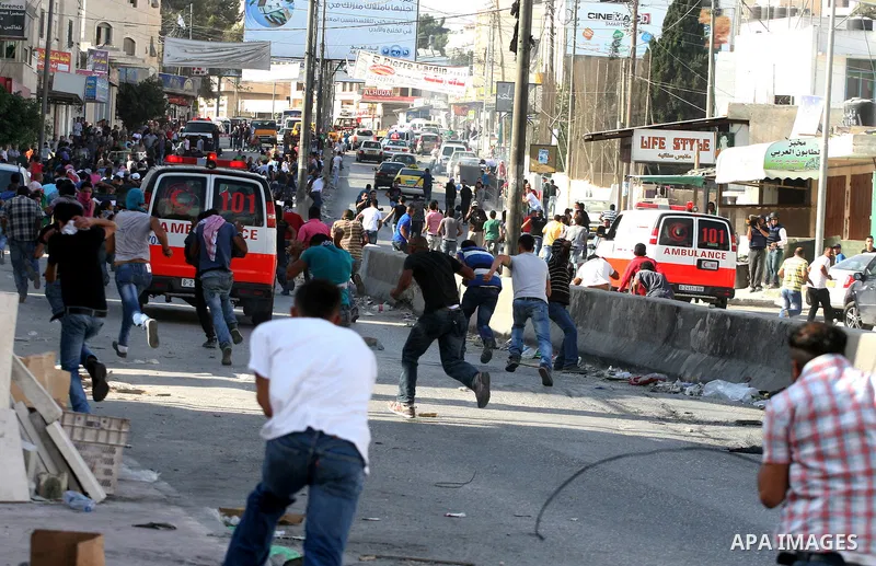 Palestinian men throw stones at Israeli soldiers during riots at the Qalandia checkpoint near Ramallah, on 23 September 2011. Reports state that Israeli security services were on high alert across the country, poised to...
