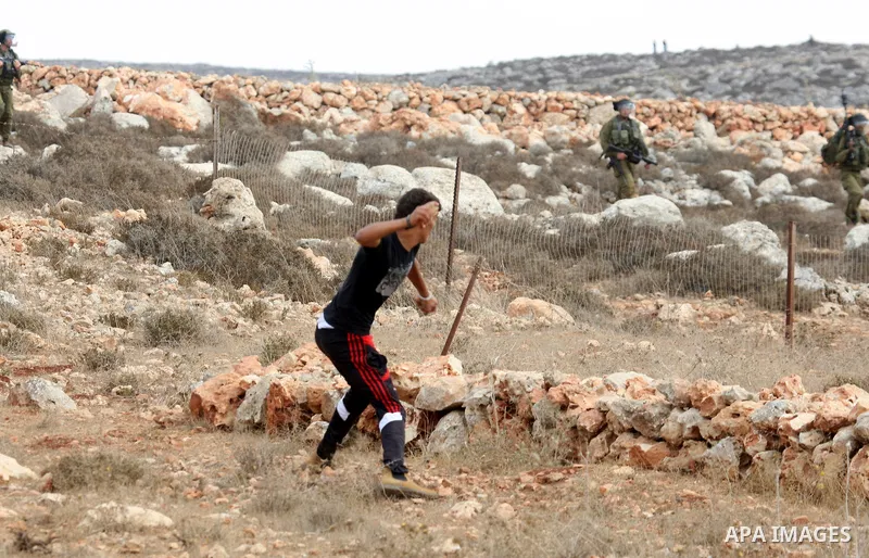 A Palestinian youth throws stones toward Israeli troops during clashes in the West Bank village of Qusra, south of Nablus, on September 23, 2011. A Palestinian man was shot dead by Israeli troops in clashes which erupted...