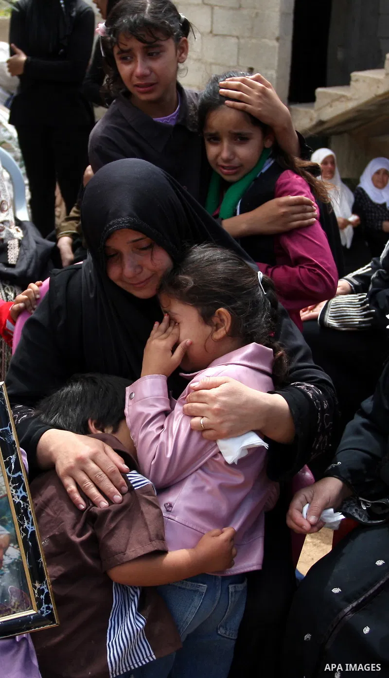 Palestinian Samir Badran, center, embraces her children during the funeral of her husband Issam in the West Bank village of Qusra near Nablus, on Sept. 24, 2011. Badran was shot dead Friday during a clash with Israeli so...