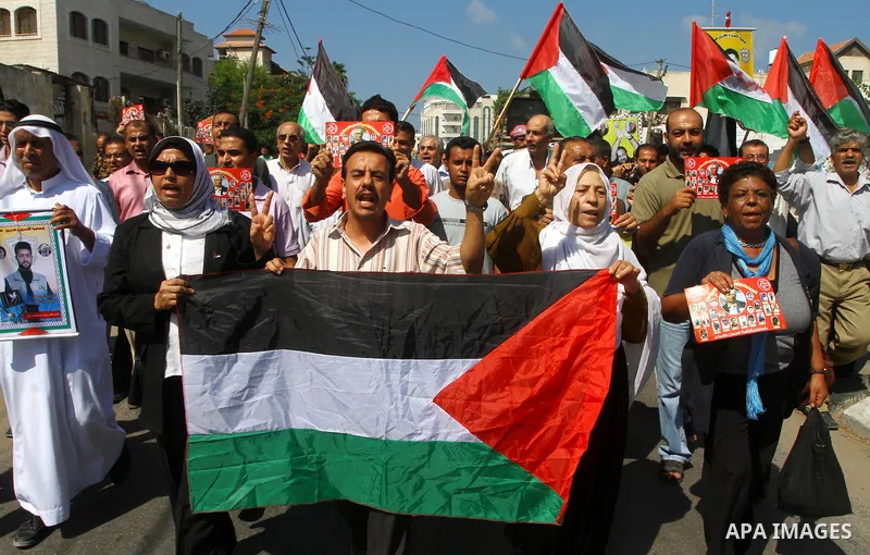 Palestinians shout slogans while holding the Palestinian flag during a protest calling for the release of imprisoned relatives from Israeli jails outside the International Committee of the Red Cross (ICRC) in Gaza City o...