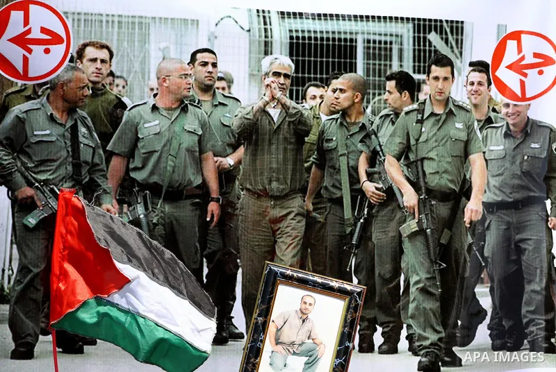 Palestinians hold a big poster while waving the Palestinian flag, during a protest calling for the release of imprisoned relatives from Israeli jails, outside the International Committee of the Red Cross (ICRC)in Gaza Ci...