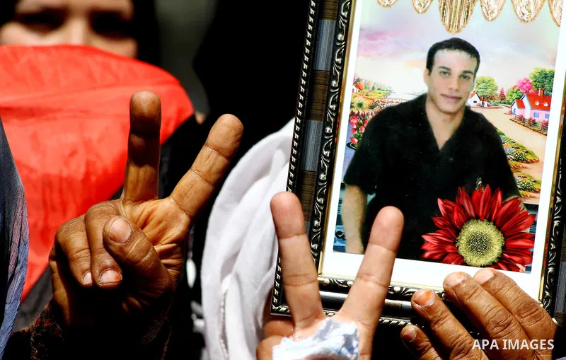 Palestinians hold pictures of relatives held in Israeli jails while signing a victory, during a protest calling for their release, outside the International Committee of the Red Cross (ICRC), in Gaza City, on Sept. 29, 2...