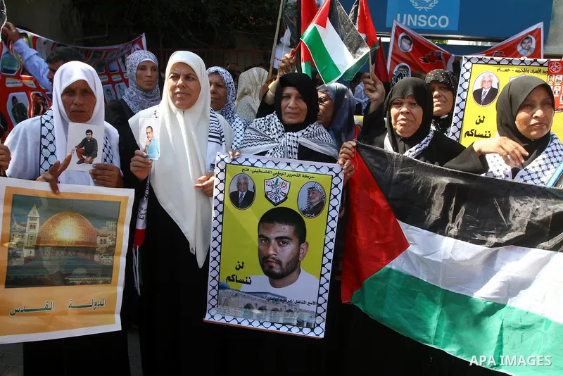 Palestinians hold the Palestinian flag and pictures of relatives held in Israeli jails, during a protest calling for their release, in front of the International UNSCO headquarters in Gaza City, on Sept. 29, 2011. Photo...