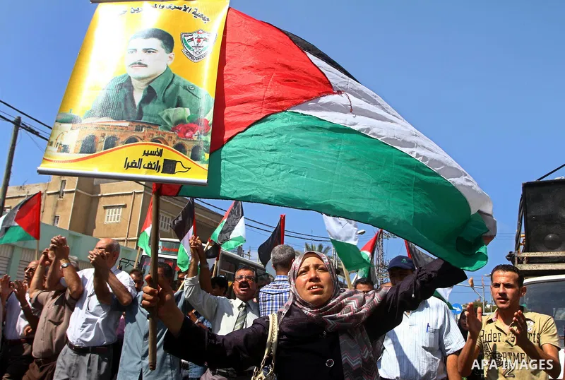 Palestinians wave the Palestinian flag while holding pictures of relatives held in Israeli jails, during a protest calling for their release, outside the International Committee of the Red Cross (ICRC)in Gaza City, on Se...