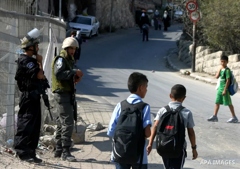 Palestinian schoolchildren walk past Israeli soldiers standing guard in the east Jerusalem neighborhood of Silwan, Thursday, Sept. 29, 2011. Israel on Tuesday approved construction of 1,100 homes for Jews on the annexed...