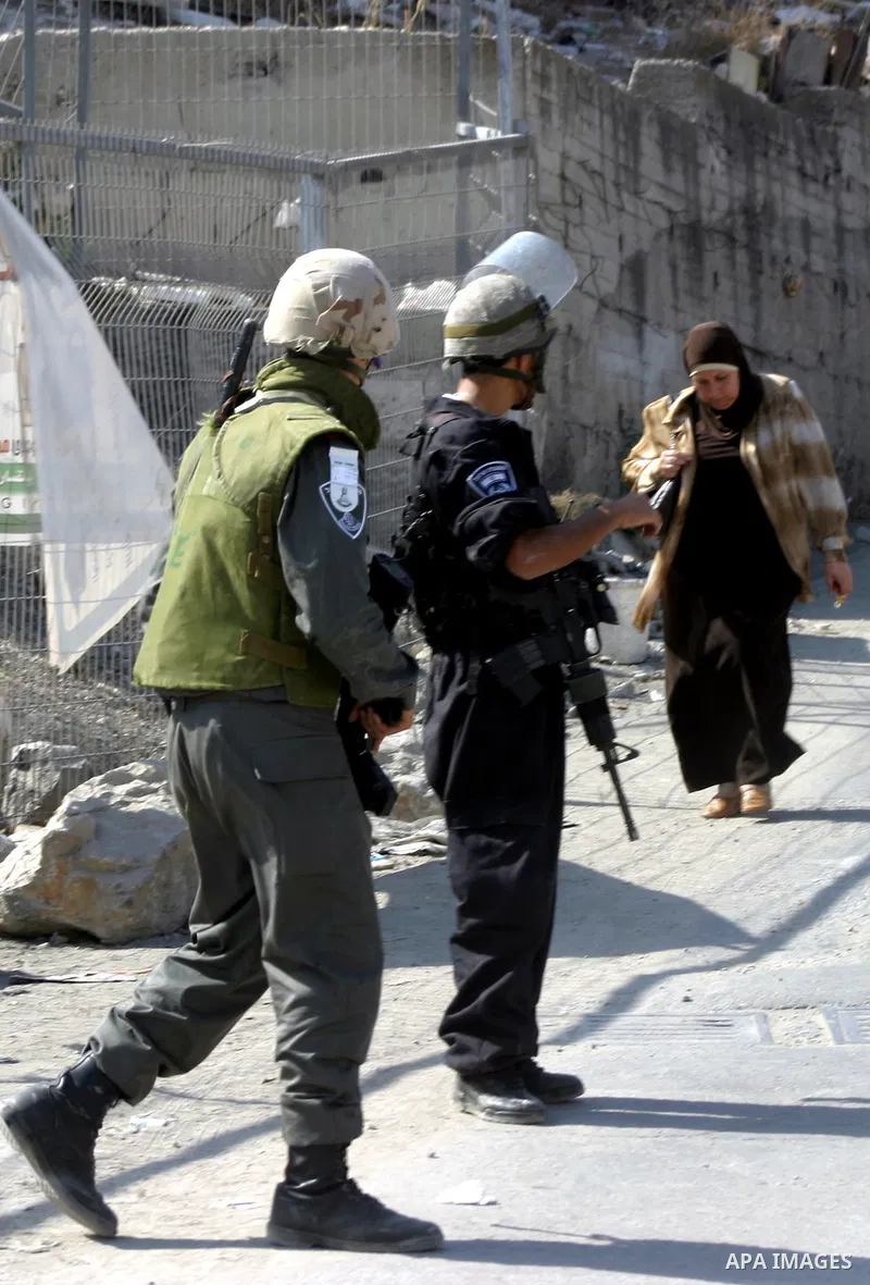 A Palestinian woman walks past Israeli soldiers standing guard in the east Jerusalem neighborhood of Silwan, Thursday, Sept. 29, 2011. Israel on Tuesday approved construction of 1,100 homes for Jews on the annexed land i...