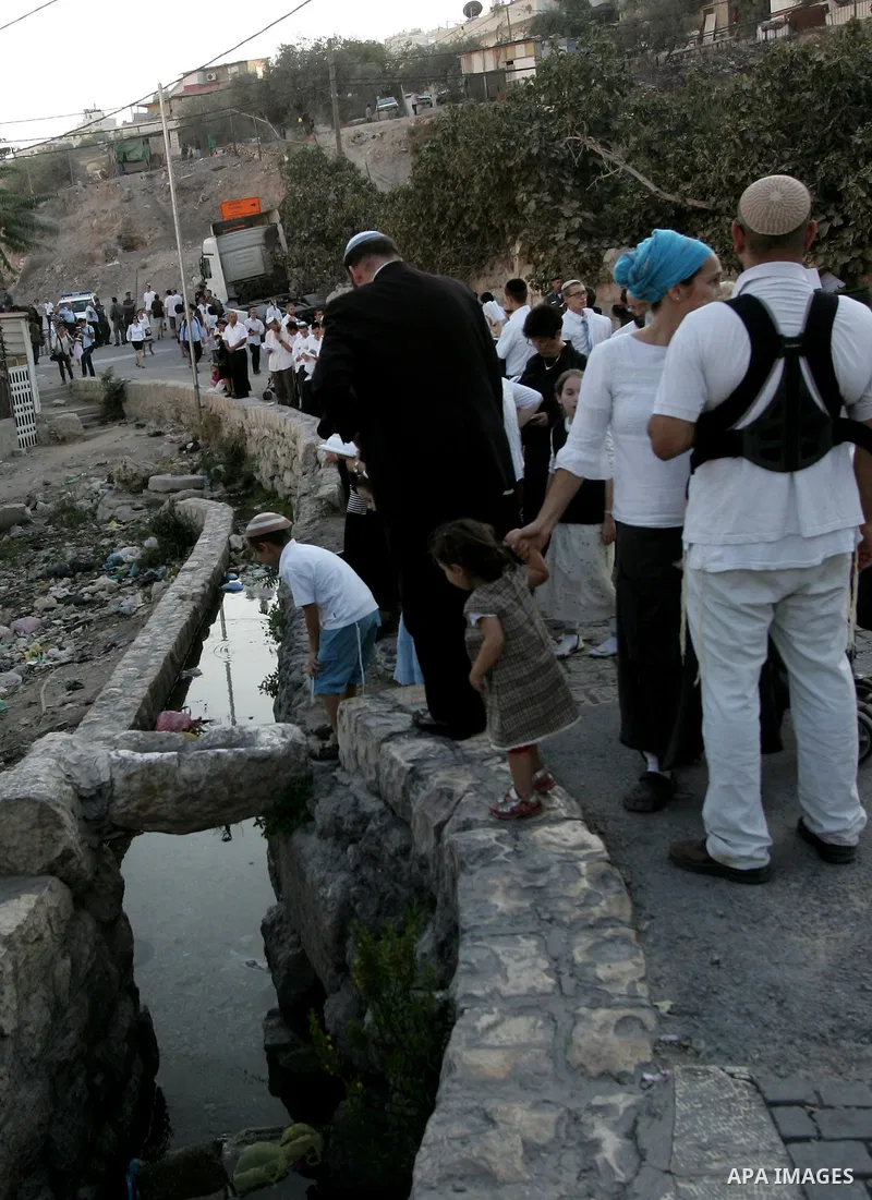 Jews gather to read prayers and perform 'Tashlich,' meaning to 'cast off,' near a small stream of water overlooking the arab East Jerusalem village of Silwan, at sun down on the first day of Jewish New Year, or Rosh Hash...