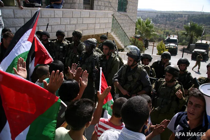 Israeli soldiers stand guard as Palestinian protestors demonstrate against the Israeli occupation in farm land close to the Palestinian village of Beit Omar near the Israeli settlement of Karmi Tsour, north the West Bank...