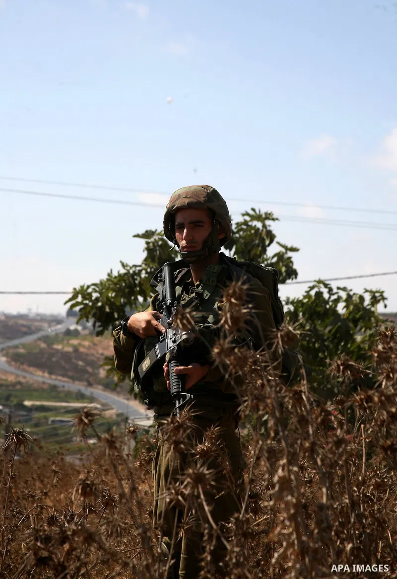Israeli soldiers stand guard as Palestinian protestors demonstrate against the Israeli occupation in farm land close to the Palestinian village of Beit Omar near the Israeli settlement of Karmi Tsour, north the West Bank...