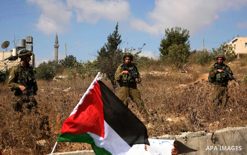 Israeli soldiers stand guard as Palestinian protestors demonstrate against the Israeli occupation in farm land close to the Palestinian village of Beit Omar near the Israeli settlement of Karmi Tsour, north the West Bank...