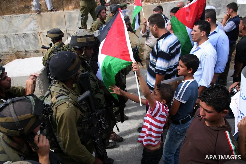 Israeli soldiers stand guard as Palestinian protestors demonstrate against the Israeli occupation in farm land close to the Palestinian village of Beit Omar near the Israeli settlement of Karmi Tsour, north the West Bank...